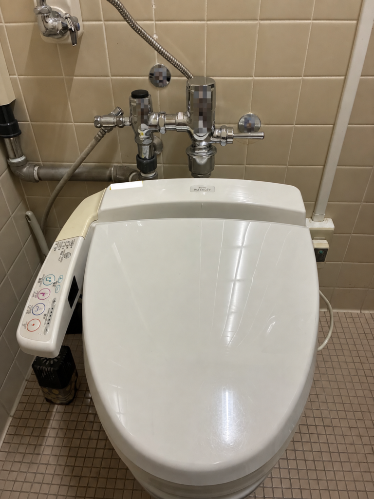 フラッシュバルブ式トイレに設置された交換前のTOTOウォシュレット