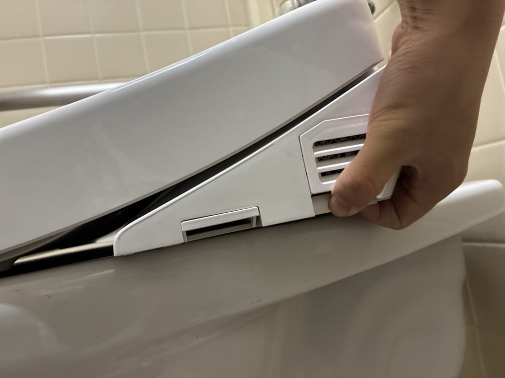ウォシュレット側面の取り外しボタンを押している様子